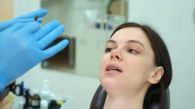 Ortodontist doktor kadın dişlerinin kapağını karbon kâğıdıyla kontrol ediyor..