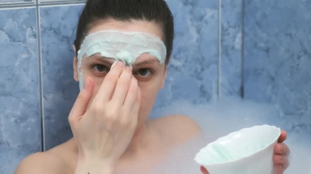 Jeune femme applique masque en alginate couché dans la salle de bain avec de la mousse à la maison. — Video