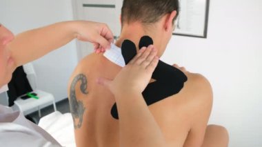 Fizyoterapist, Kinesio kasetlerini klinikte boyun omuzlarına yapıştırdı..