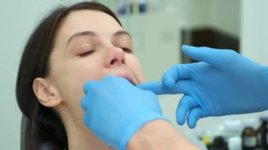 Ortodontist doktor kadın dişlerinin kapağını karbon kâğıdıyla kontrol ediyor..