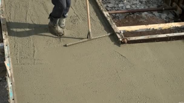 Bouwer metselaar nivelleren beton met lange troffel op de bouwplaats. — Stockvideo