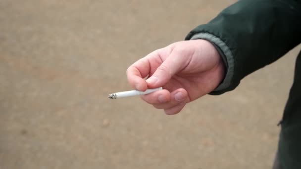 Mans ruka s doutnající cigaretou kouření špatný zvyk. — Stock video