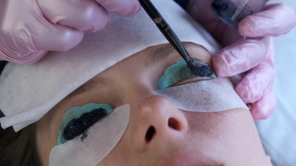 Kosmetikerin bemalt Wimpern in schwarzer Farbe in Kosmetologie-Klinik, Gesichtsnahaufnahme. — Stockvideo