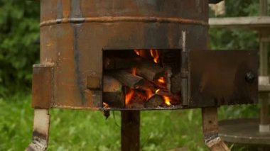 Odun, doğada yemek pişirmek için metal odun ocağında yanıyor..