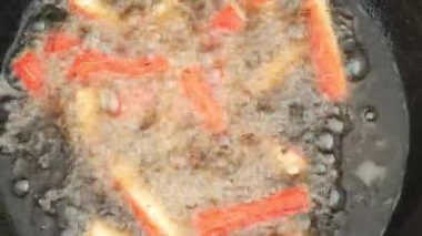 Balık kroketleri, siyah kazan kazanında kızgın yağda kızartılıyor. Yakın çekim görüntüsü..
