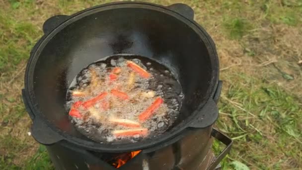 Palitos de peixe é fryng em óleo fervente em caldeirão kazan preto, vista close-up. — Vídeo de Stock
