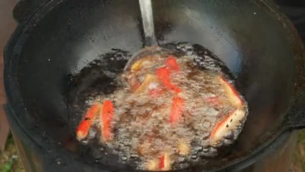 Palitos de peixe é fryng em óleo fervente em caldeirão kazan preto, vista close-up. — Vídeo de Stock