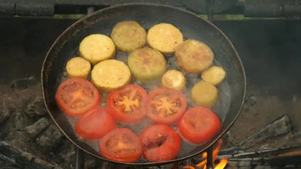 Кусочки цуккини и помидоров жарят на сковороде с маслом в гриле. — стоковое видео