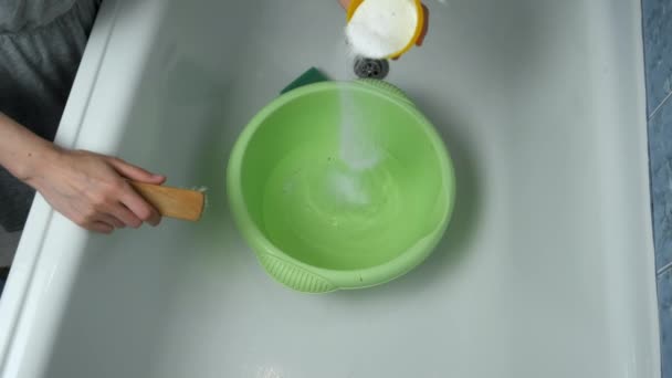 Женщина готовит воду в раковине к стирке одежды, наливает стиральный порошок. — стоковое видео