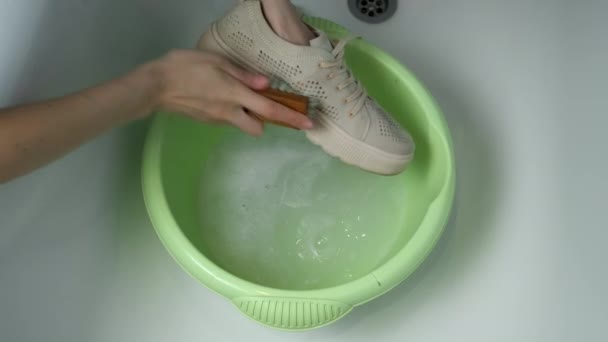 Femme lave les chaussures de sport dans le bassin à l'aide d'une brosse à mains, les mains gros plan. — Video