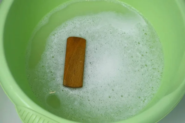 Мыльная вода в раковине с кистью, приготовленной для ручной стирки одежды. — стоковое фото