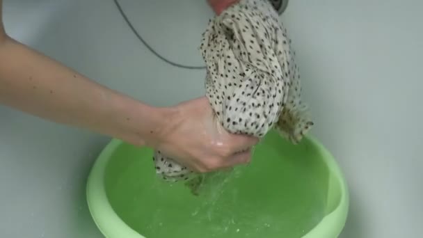 A woman wrings out a hand-washed dress over a basin, closeup view. — Stock Video