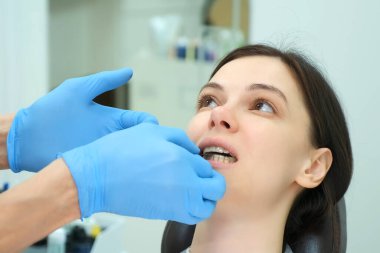 Ortodontist doktor kadın dişlerinin kapağını karbon kâğıdıyla kontrol ediyor..