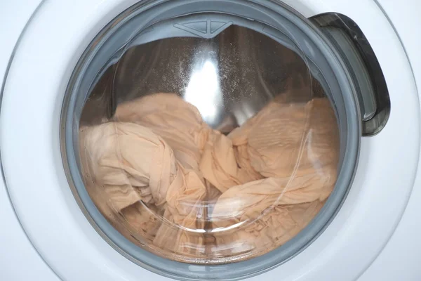 Çamaşır makinesi bej çarşafları sarıyor, pencereyi kapatıyor.. — Stok fotoğraf
