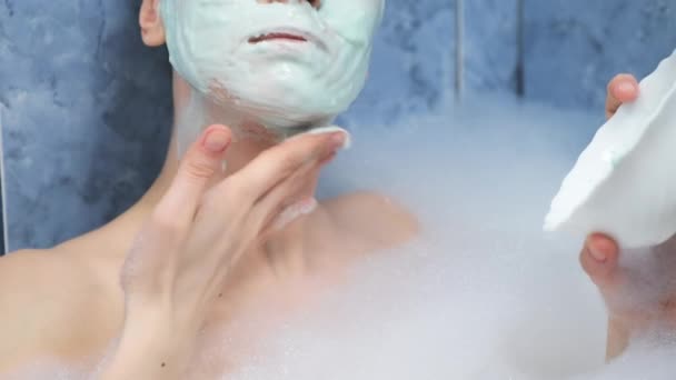 Face of woman is applying alginate mask lying in bathroom with foam at home. — Stock Video