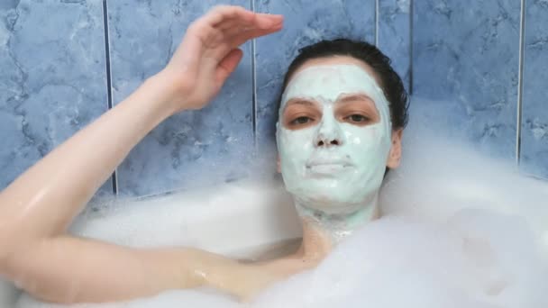 Młoda kobieta z alginianową maską relaksująca się w łazience z pianką w domu. — Wideo stockowe