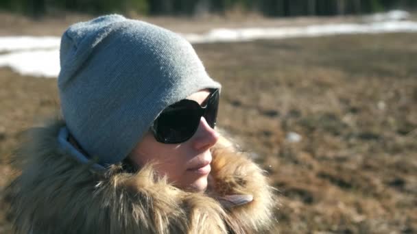 Portrait de jeune femme en chapeau, lunettes de soleil et veste en fourrure sur la nature. — Video