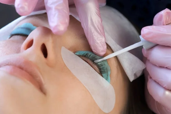 Kosmetikerin appliziert Lösung auf Frauen-Wimpern zum Laminieren von Lifting-Wimpern. — Stockfoto