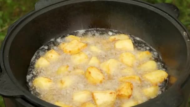 Рудди вкусный картофель жарится в котле в масле на природе в огне, крупный план. — стоковое видео