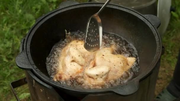 Pollo fritto in cazan nero con olio bollente in stufa a legna sulla natura. — Video Stock