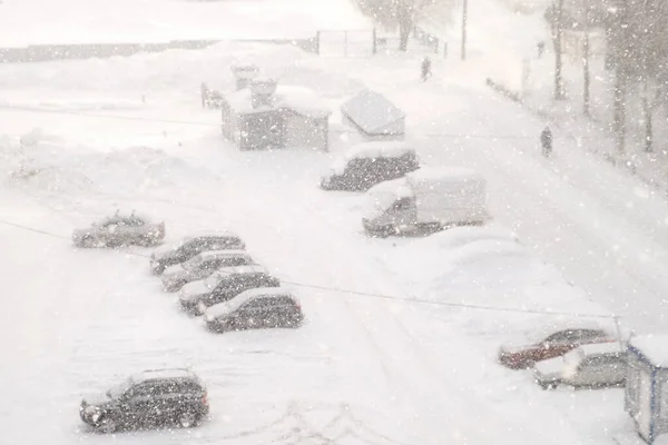 Urban landscape in blue colors in heavy snowfall, blizzard, snowstorm on street.