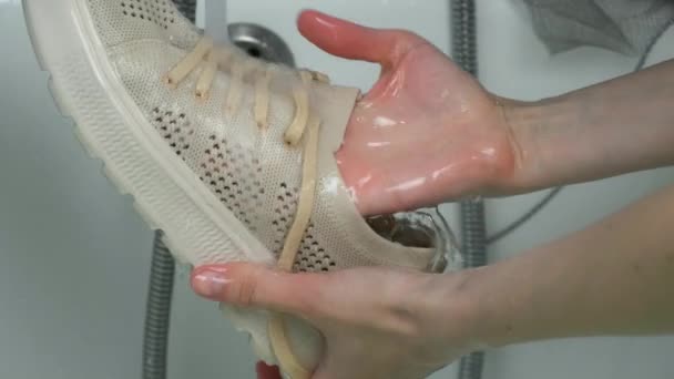 Vrouw is wassen sport schoenen in badkamer door handen, close-up handen. — Stockvideo