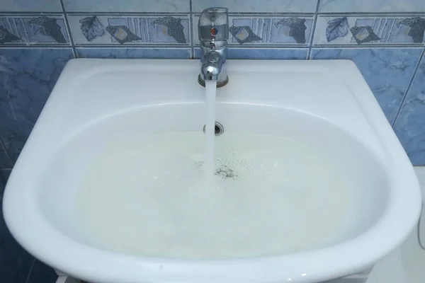 Dräneringshålet i diskhon är igensatt och vatten samlas upp från kranen. — Stockfoto