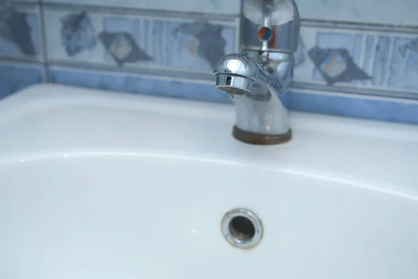 Vatten droppar från en kran i vit handfat i badrummet, närbild. — Stockfoto