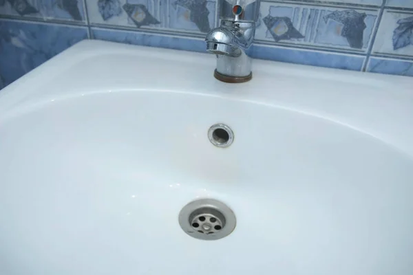Vatten droppar små droppar från kranen i handfat i badrummet, närbild. Royaltyfria Stockfoton