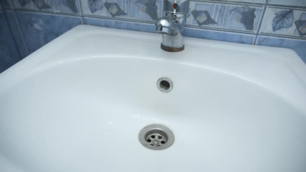 Água gotejando pequenas gotas de torneira em pia no banheiro, vista close-up. — Vídeo de Stock