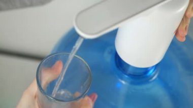 Kadın elleri su soğutucusundan bardağa su döker..