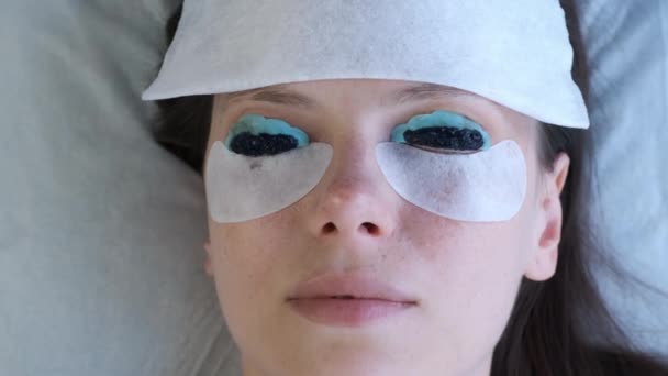 Vrouw op wimperlift lamineren schilderij procedure in schoonheidskliniek, close-up. — Stockvideo