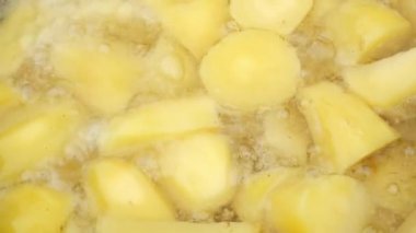 Patates, kaynayan yağda kazanda kızarıyor. Yakın çekim..