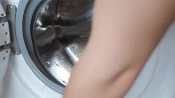 Mans charge la machine à laver avec du linge de lit beige, buanderie à la maison. — Video