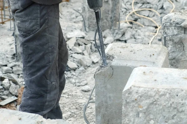 Destruction of a concrete pile with drill machine jackhammer, closeup view.