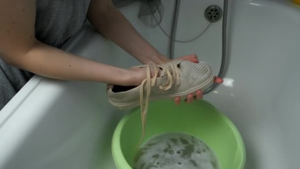 Femme lave les chaussures de sport dans le bassin à l'aide d'une éponge à la main, à gros plan les mains. — Video