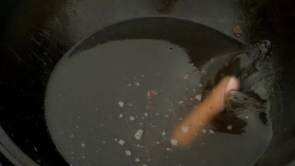 Man lägger korv i kokande olja till stekning i kittel, närbild. — Stockvideo