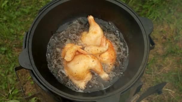 Pollo fritto in cazan nero con olio bollente in stufa a legna sulla natura. — Video Stock