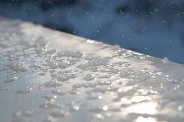 Spring drops and melting snow on the windowsill outside the window, closeup. Spring drops and melting snow on the windowsill outside the window, closeup.