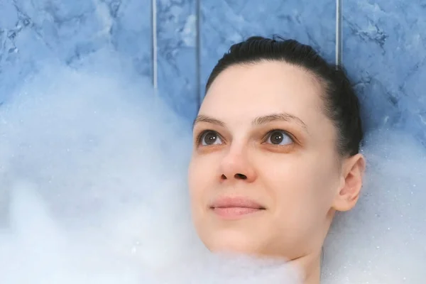 Mujer joven con los ojos cerrados relajante tumbado en el baño con espuma después de un día ocupado. — Foto de Stock