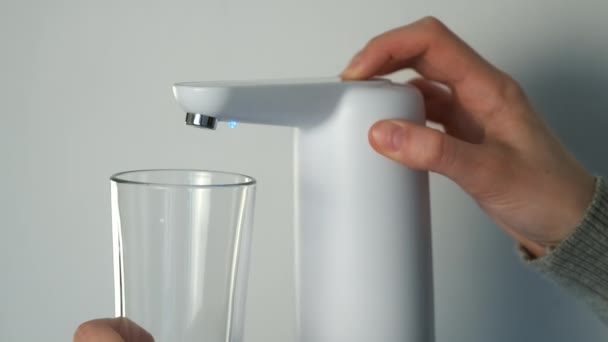 Mans handen gieten water in glas uit een automatische waterkoeler, close-up zicht. — Stockvideo