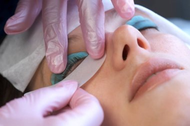 Kozmetik uzmanı müşterilerin altına göz bandı yapıştırıyor..