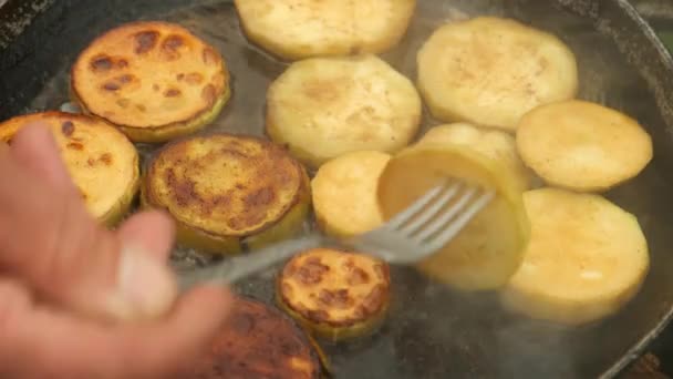 Man steker en bit zucchini på stekpanna med olja på kol i grillen. — Stockvideo