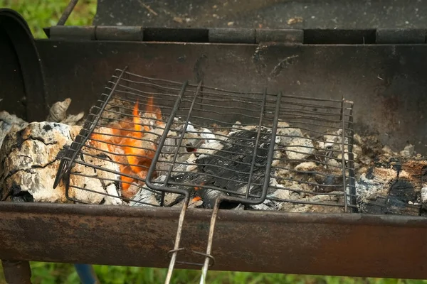 Grill grate is on the burning chargrill with hot charcoals and woods in it. — Stock Photo, Image