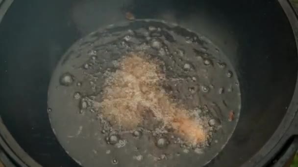 男子在烧开的油中煎腊肠在大锅黑色卡赞，特写镜头. — 图库视频影像