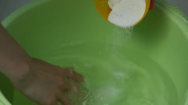 La mujer está preparando el agua en el lavabo para lavar la ropa, vertiendo polvo de lavado. — Vídeos de Stock