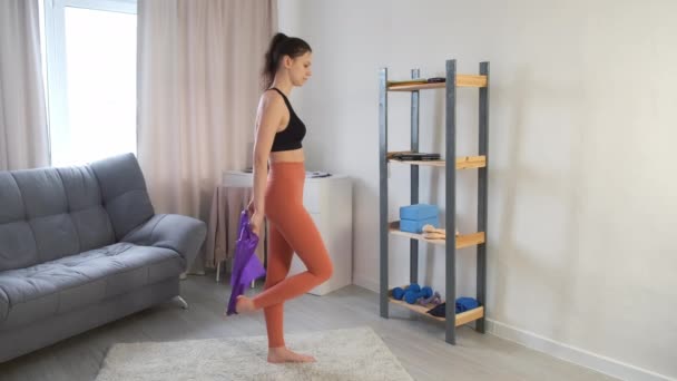 Donna in abbigliamento sportivo è stretching gamba e backbend con banda di resistenza a casa. — Video Stock