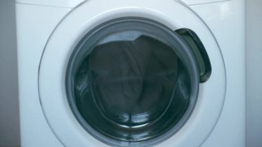 Çamaşır makinesi gri yatak örtüsünü yıkar, pencereyi kapatır..