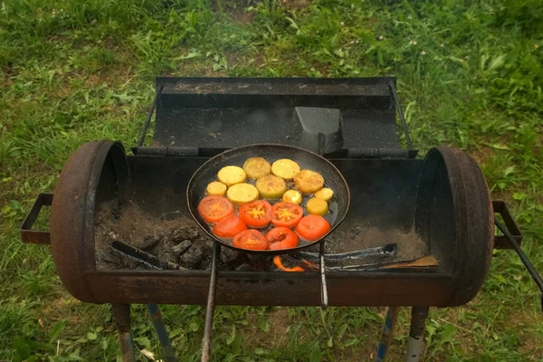 Κομμάτια από κολοκυθάκια και ντομάτες τηγανίζονται σε τηγάνι με λάδι σε σχάρα. — Φωτογραφία Αρχείου