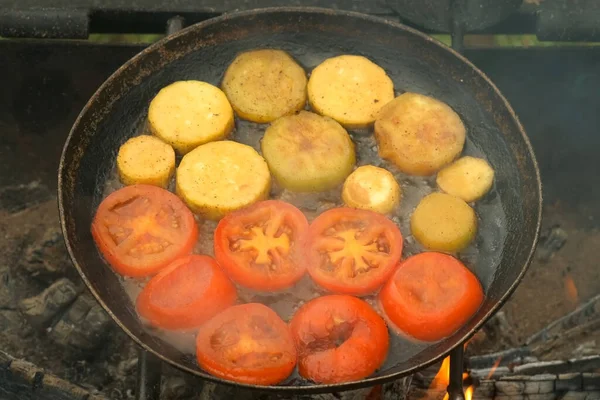 Slices of zucchini and tomatoes are frying on frying pan with oil in chargrill. — Stock Photo, Image